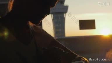 金色夕阳下，一位女士坐在机场候机楼的窗边，手里拿着笔，用着智能手表
